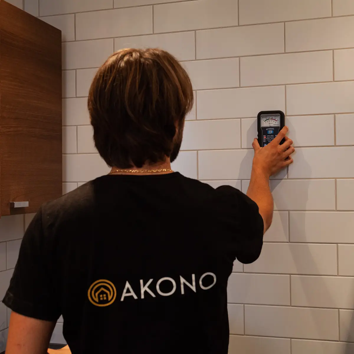 Akonos tekniker mäter med instrument mot en vägg